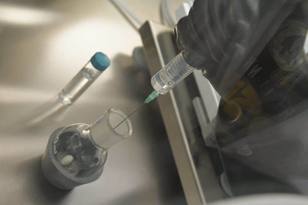 Cette photo représente l'introduction d'un réactif liquide dans un flacon à l'aide d'une seringu